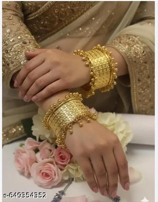 Samridhi pack of 2 Gold Plated Bangles The bangles are wide gold bangles or kadas (a type of thick bangle or bracelet, often worn singly or in pairs)